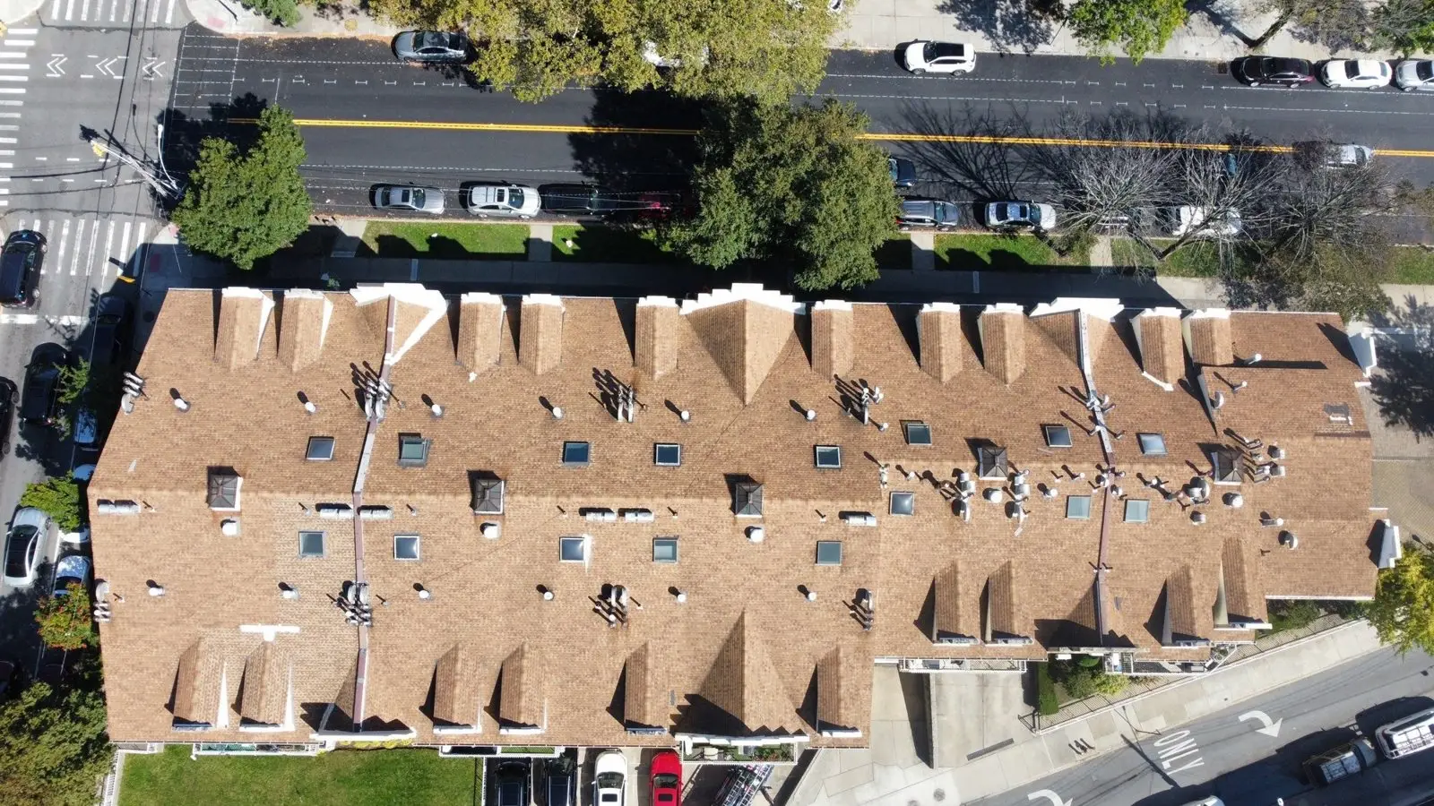 Drone view of a condo roof along a busy street