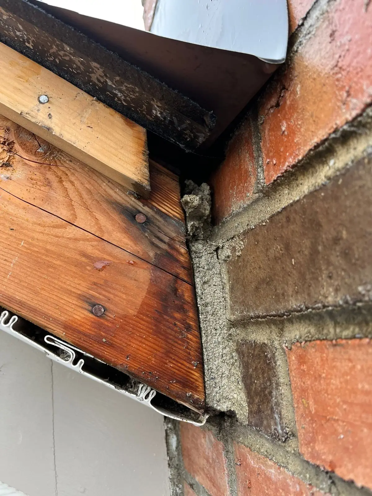 Rotted wood fascia and soffit at the corner of a brick house