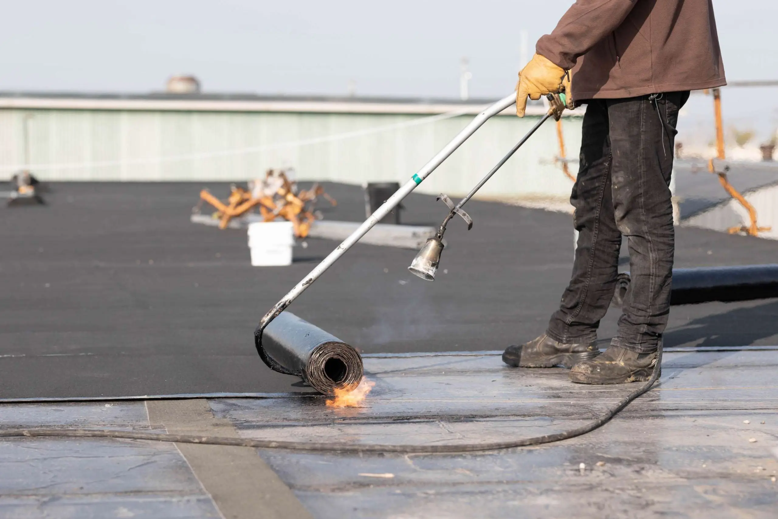 Roofer installing a modified bitumen flat roof with a torch