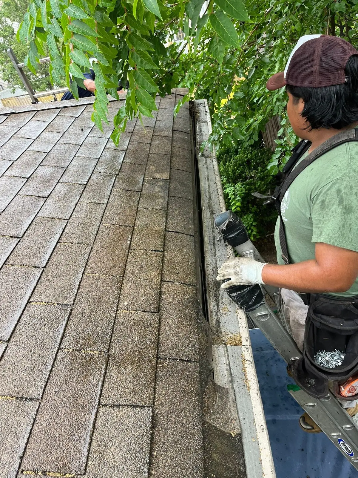B&B crew member working on a gutter along a shingle roof