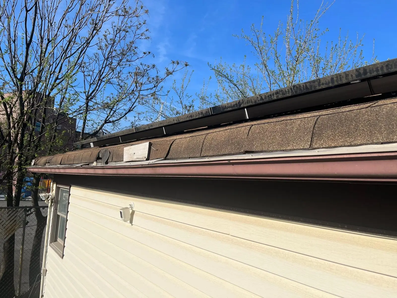 New brown seamless gutter installed along the fascia of a house