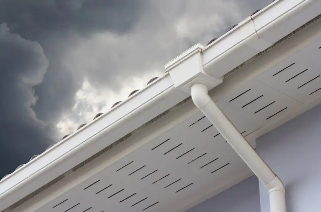 New seamless gutter on a house roof edge against a stormy sky