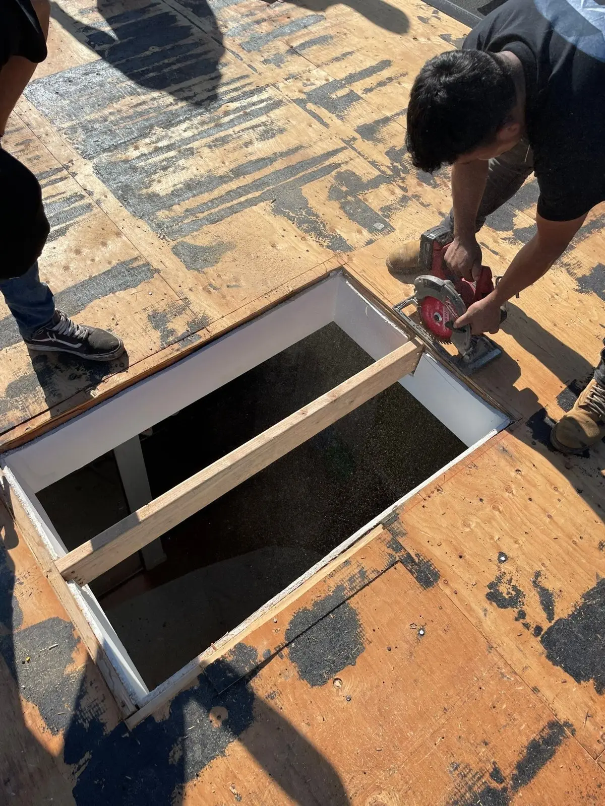 B&B roofer cutting and framing a new skylight opening in the roof deck