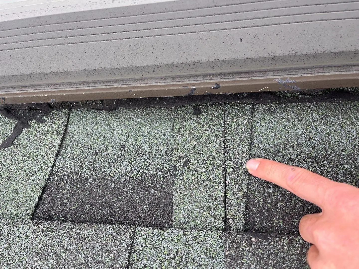 Damaged shingles next to a skylight curb