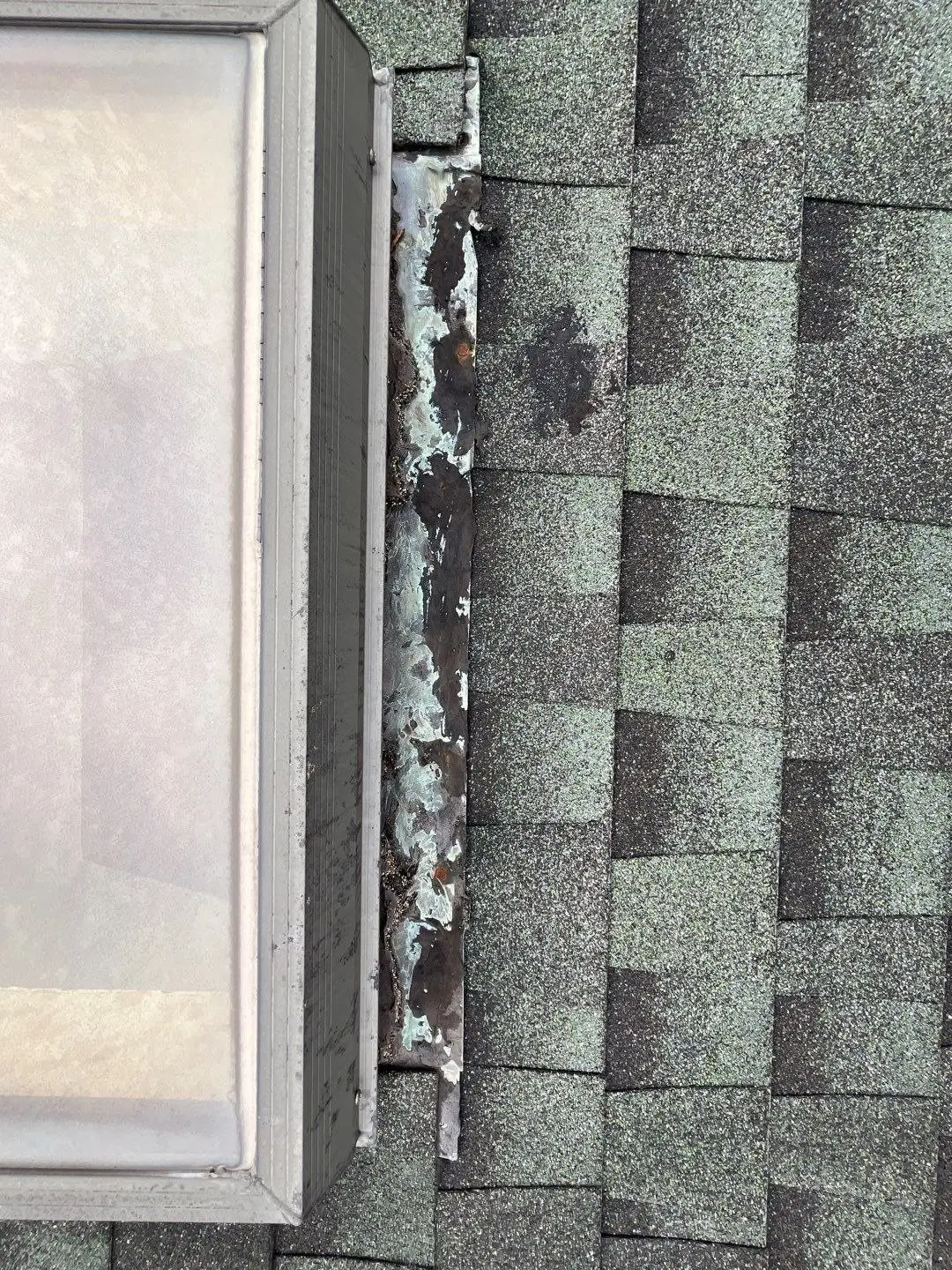 Old skylight with failed sealant and cracked caulk along the frame