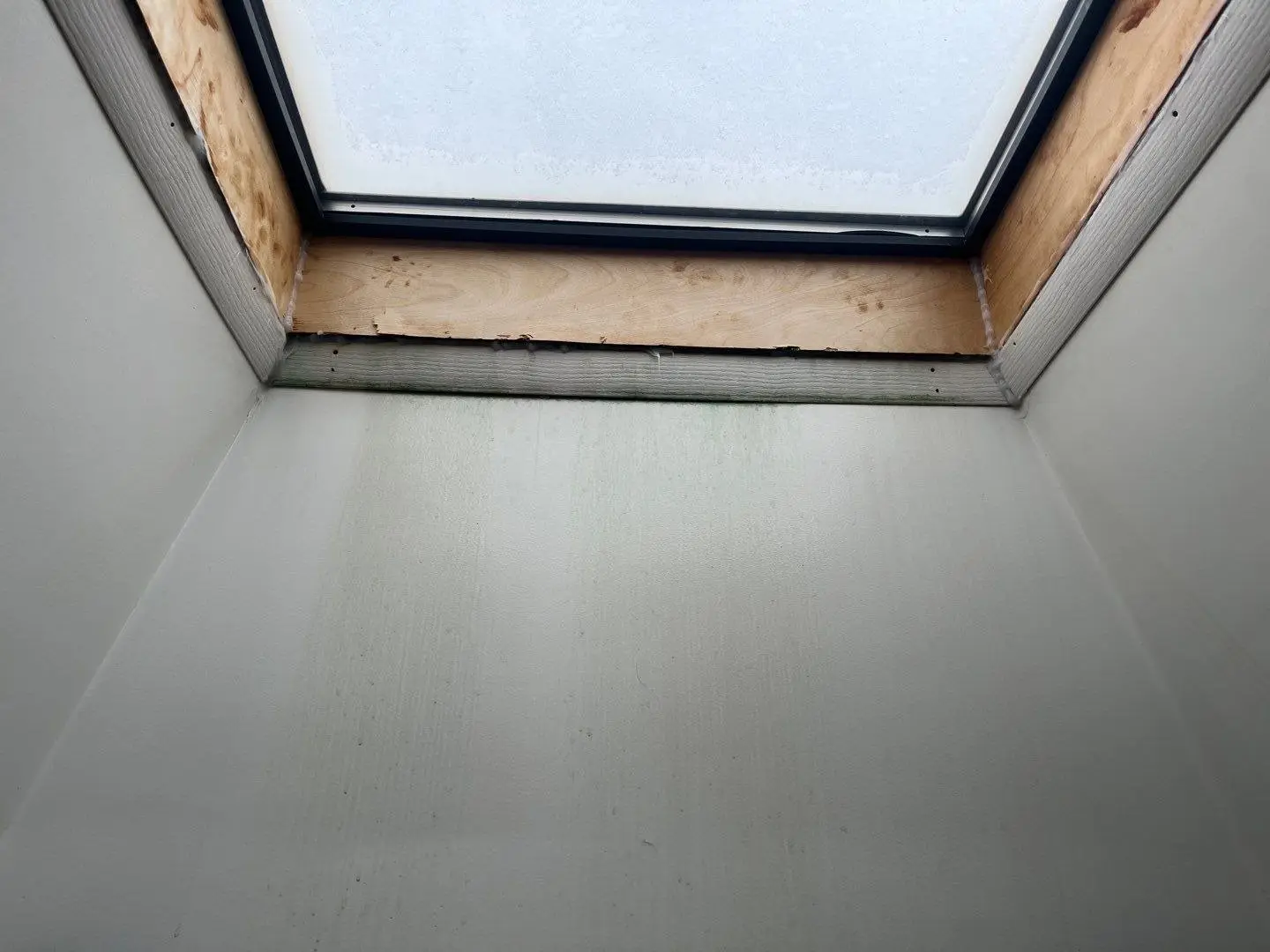 Skylight well seen from inside with exposed wood framing at the top